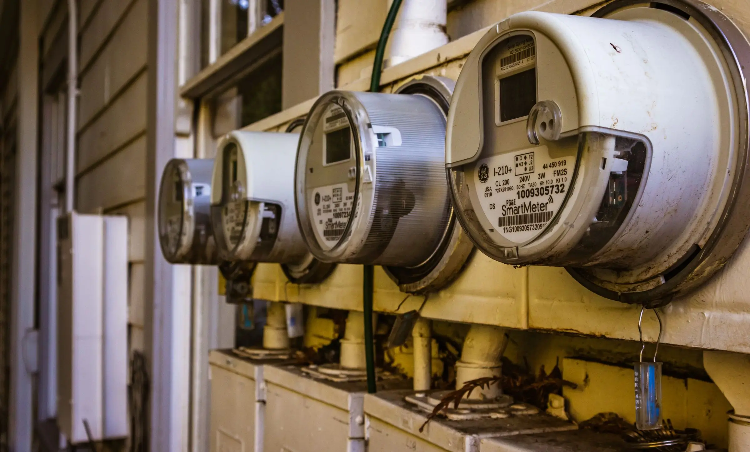 A row of round smart electricity meters on the outside wall of a building, the nearest one in sharp focus.